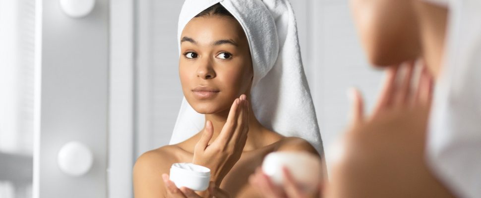 Girl Holding Face Cream Product Hydrating Skin In Bathroom