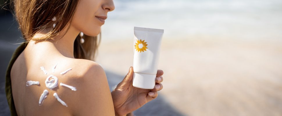 Woman with sunscreen lotion on the beach